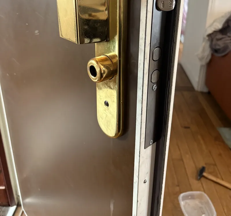 Serrure en applique dorée et son cylindre sur une porte métallique, photo d'une intervention de France Serrures