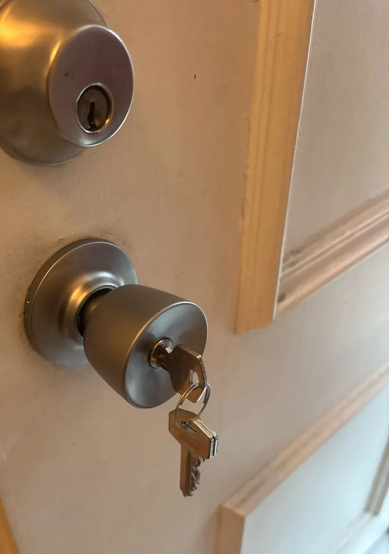Serrure à bouton et verrou à cylindre posés sur une porte d'entrée